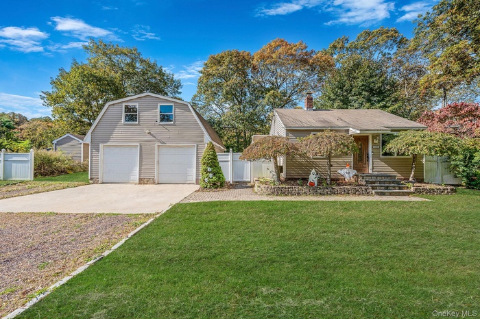 View of front of property with a gambrel roof, an outdoor structure, a chimney, driveway, and a detached garage