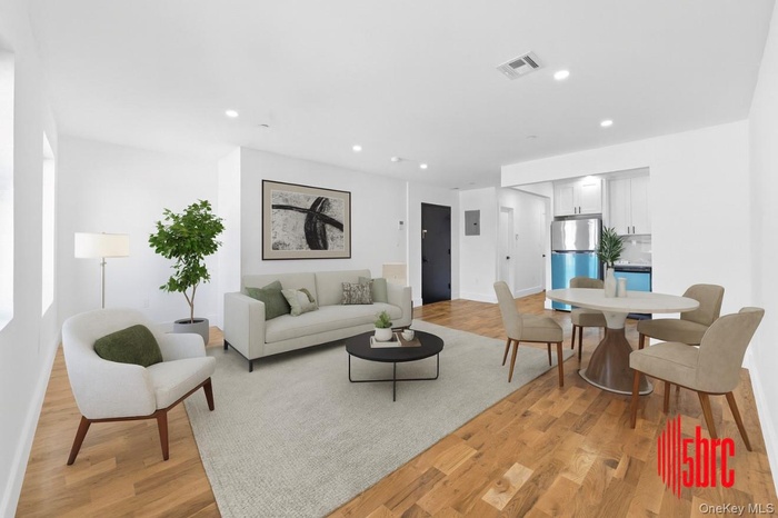 Living area featuring light wood finished floors, recessed lighting, and electric panel