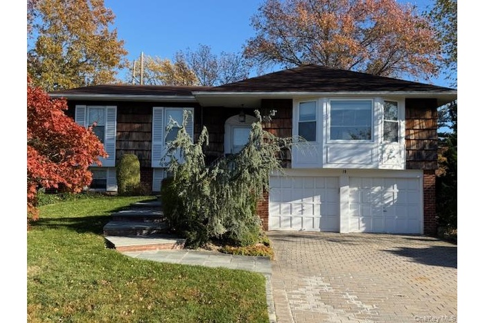 Split foyer home featuring brick siding, driveway, and an attached garage
