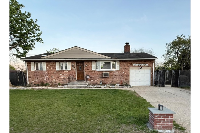 Ranch-style home featuring concrete driveway, brick siding, an attached garage, and a chimney