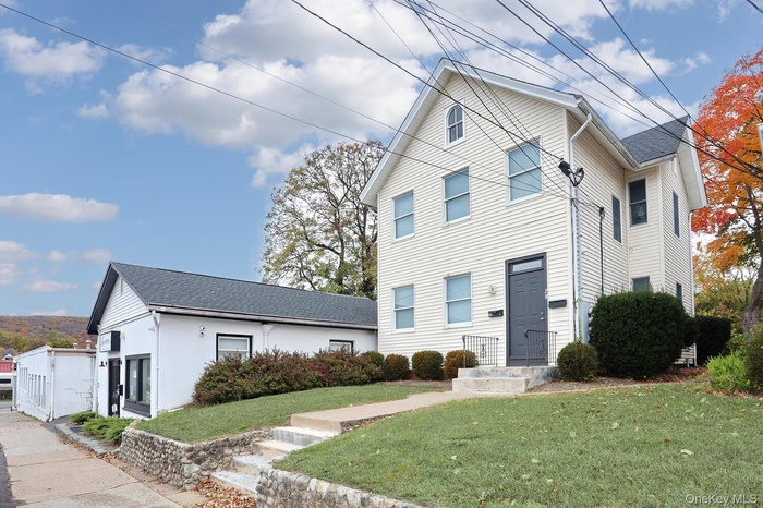 Traditional-style home with a front yard and a shingled roof