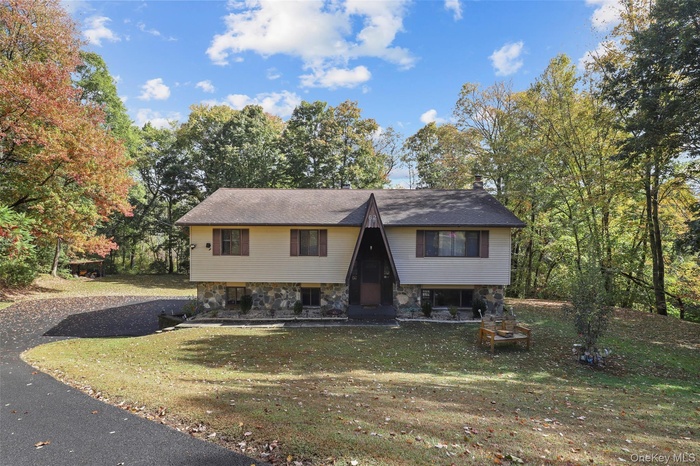View of front of house with a front yard, a chimney, and driveway