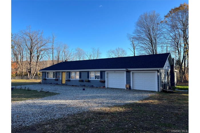 Single story home featuring an attached garage and gravel driveway