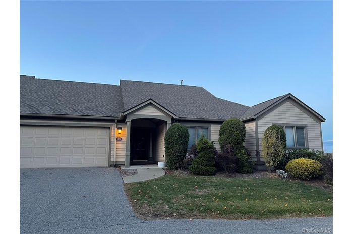 Ranch-style home with roof with shingles, a front yard, asphalt driveway, and a garage