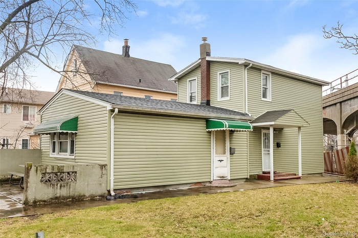 Rear view of house featuring a chimney and a shingled roof