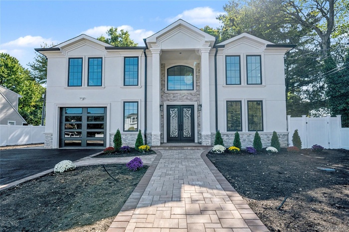 Greek revival house with stone siding, asphalt driveway, stucco siding, and a garage