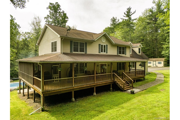 Rear view of property with covered porch, a yard, an outdoor pool, and a shingled roof