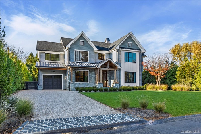 View of front of home with a front lawn, driveway, a chimney, a garage, and a porch