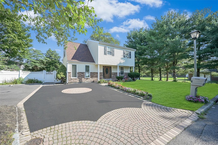 View of front of home with fence, stone siding, and a front yard