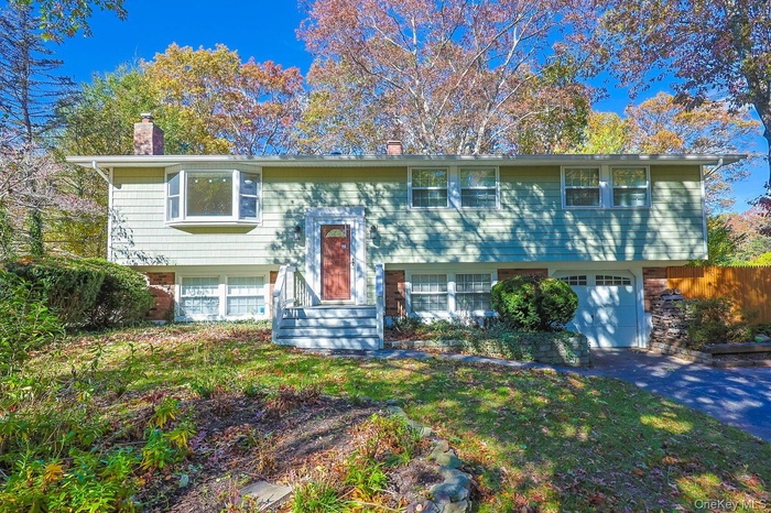 Split foyer home featuring a chimney, an attached garage, and driveway