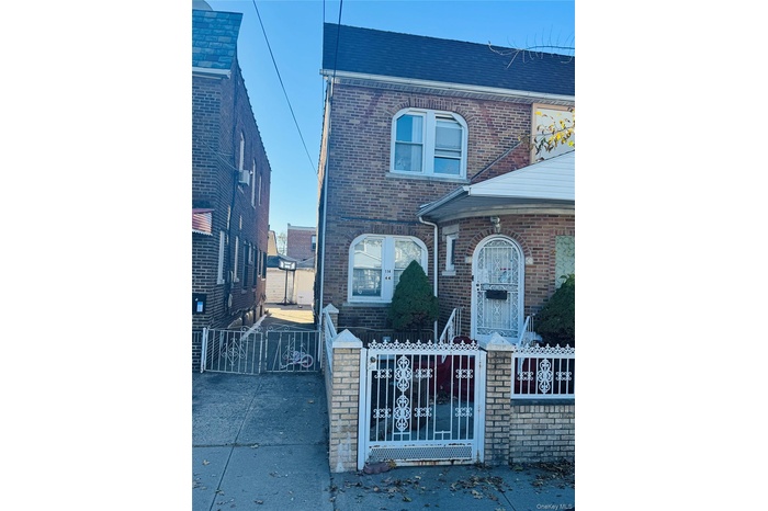 Traditional home featuring a gate, a fenced front yard, and brick siding
