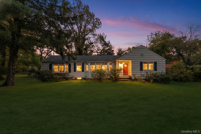 Back of property at dusk with a lawn