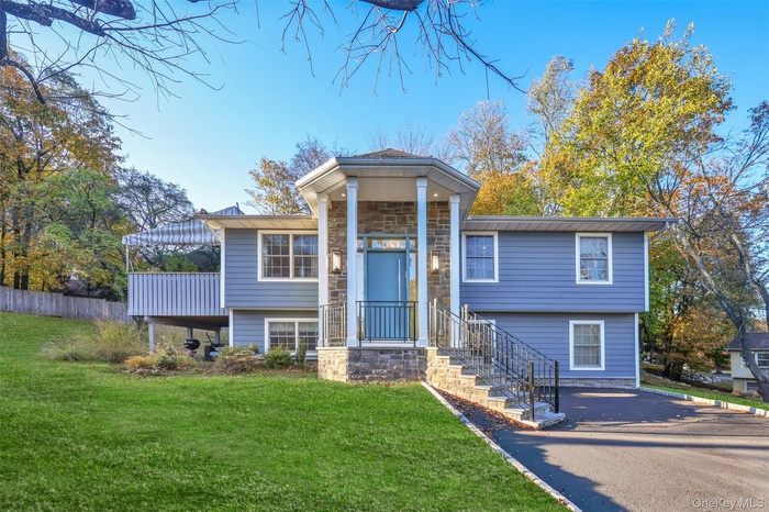 View of front of home with stone siding and a front lawn