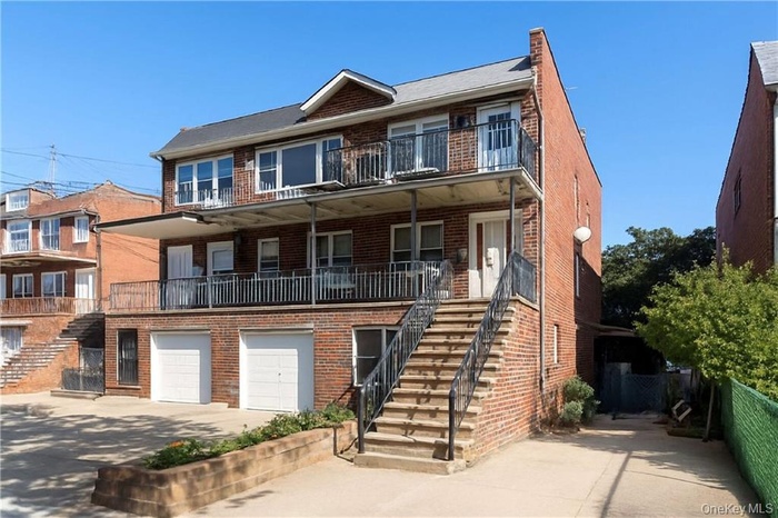 View of front of house with stairs, brick siding, and driveway