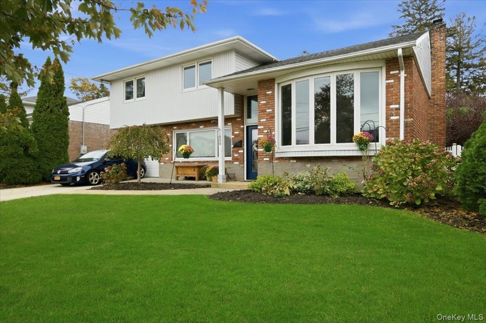 Tri-level home with brick siding, a front yard, and a chimney