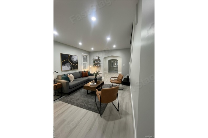 Virtually Staged/ Living room with arched walkways, light wood-style floors, and recessed lighting