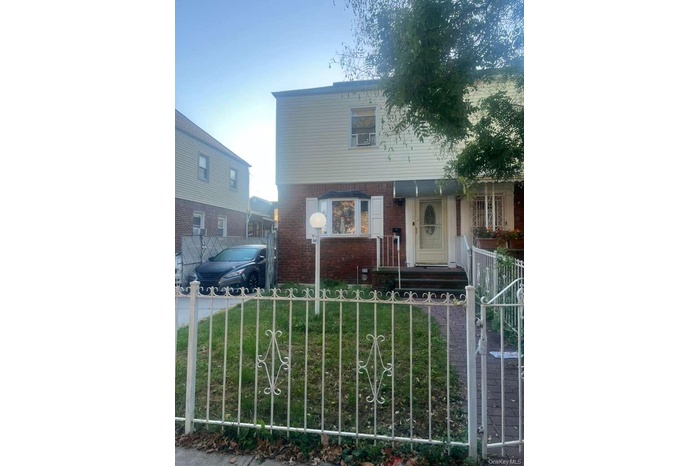 Colonial house with a fenced front yard, brick siding, and a gate
