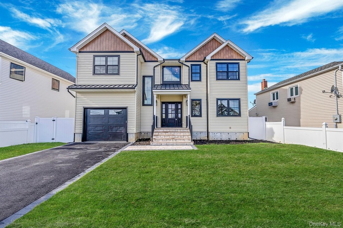 View of front of house featuring asphalt driveway, a standing seam roof, a gate, a metal roof, and a garage