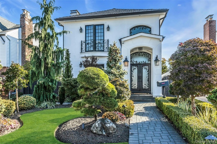 View of exterior entry featuring stucco siding, a lawn, and a chimney