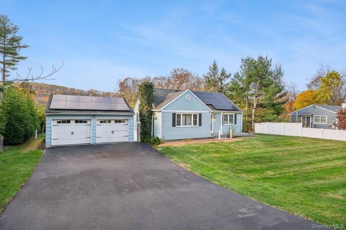 View of front of home featuring solar panels and a garage. Staged