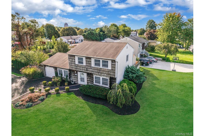 Colonial inspired home with a front lawn, roof with shingles, and driveway