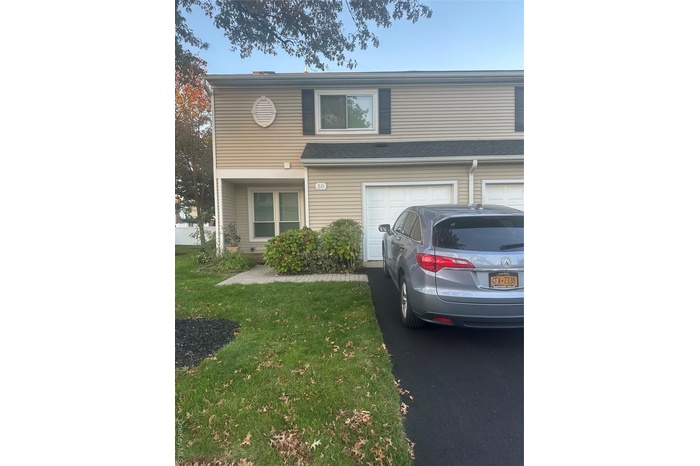 Traditional-style home featuring a garage, a front lawn, and asphalt driveway