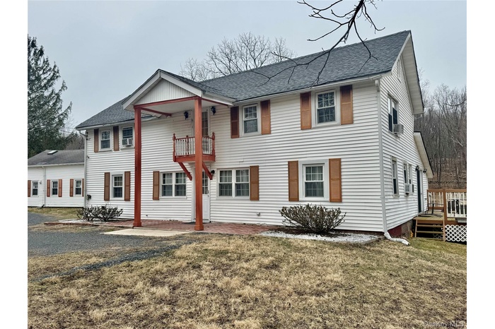1 - Colonial home featuring a balcony, a front lawn, and roof with shingles