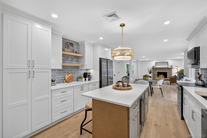 Kitchen featuring backsplash, a fireplace, light wood-type flooring, open shelves, and recessed lighting