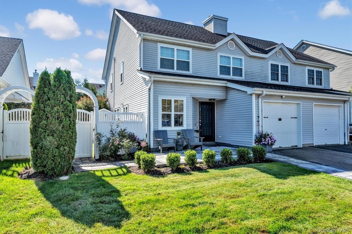 Traditional home featuring a gate, a chimney, driveway, an attached garage, and a shingled roof
