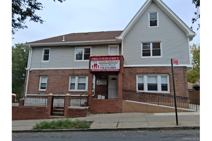 View of front facade featuring brick siding and a fenced front yard
