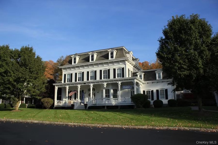 Victorian home featuring mansard roof, a front lawn, and a porch