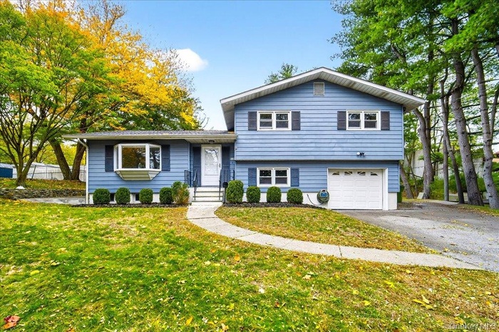 Split level home with a front yard, an attached garage, and asphalt driveway