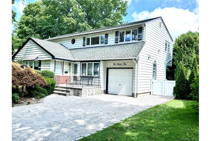 View of front of house with a shingled roof, a garage, and decorative driveway