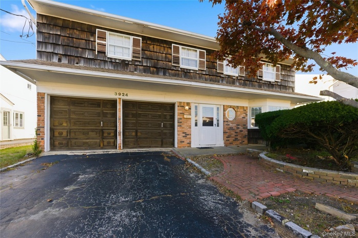 View of front of house with driveway, brick siding, and a garage
