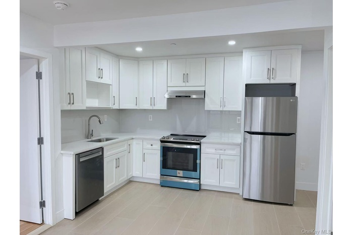 Kitchen with stainless steel appliances, white cabinetry, recessed lighting, extractor fan, and light stone counters