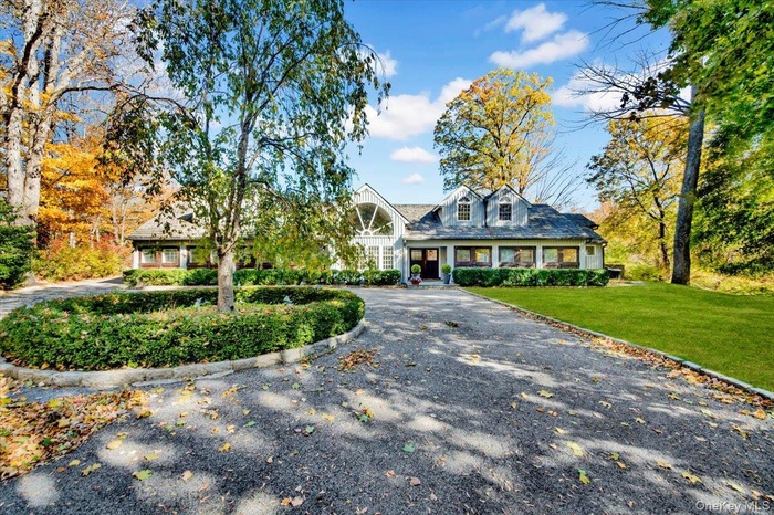 Cape cod house featuring curved driveway, a front lawn, and a porch