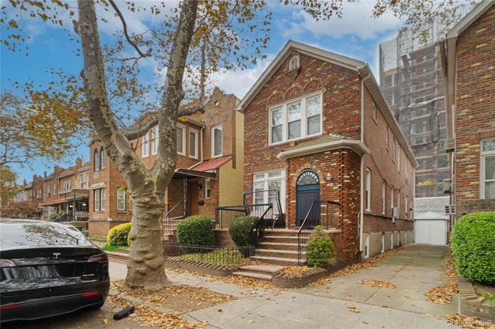 View of front of home featuring brick siding, a residential view, and an outbuilding