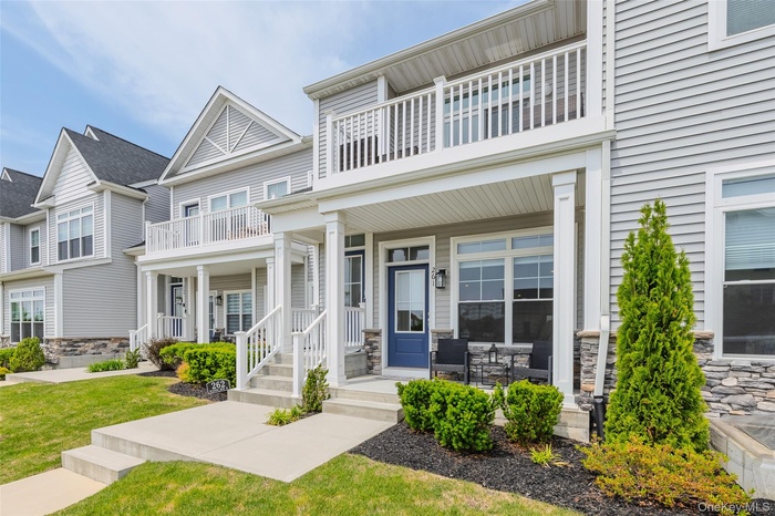 View of front of house with a balcony, stone siding, a residential view, and a porch