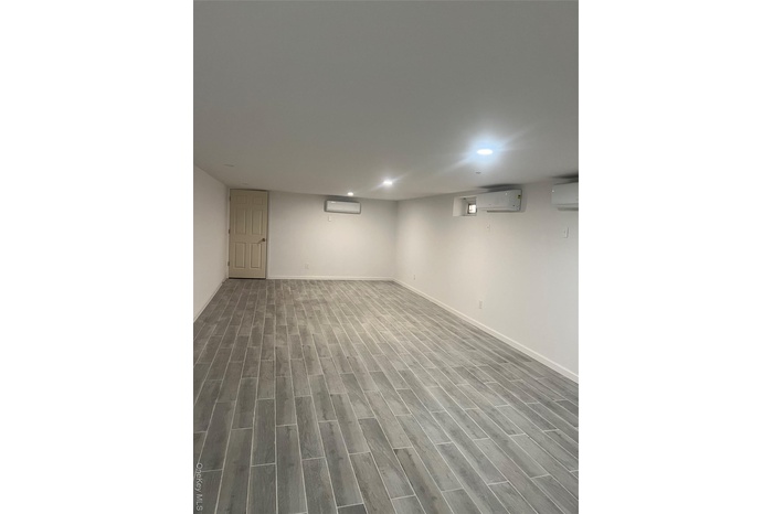 Finished basement featuring wood finished floors, a wall unit AC, and recessed lighting