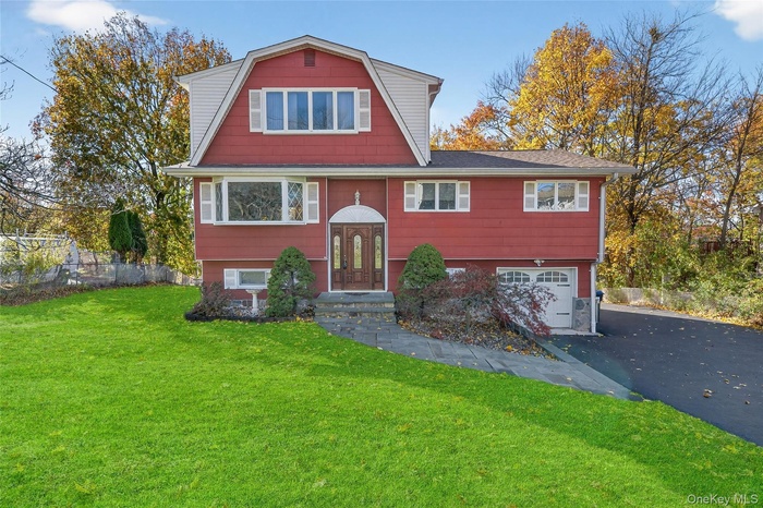 View of front of home with a garage, asphalt driveway, a front yard, a gambrel roof, and roof with shingles