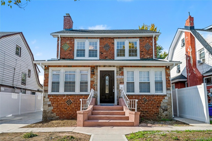 Traditional-style home featuring brick siding, a chimney, and stone siding