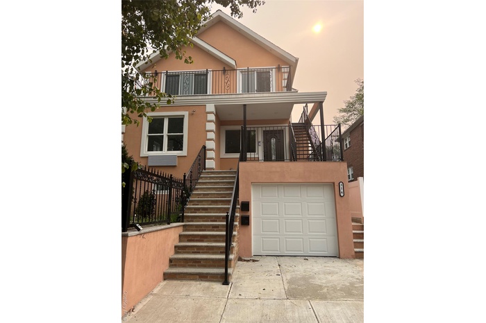 View of front of house with stairway, stucco siding, driveway, an attached garage, and a balcony
