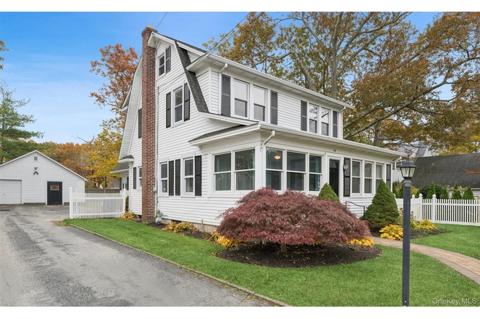 Colonial inspired home featuring a detached garage, a sunroom, an outdoor structure, and a chimney