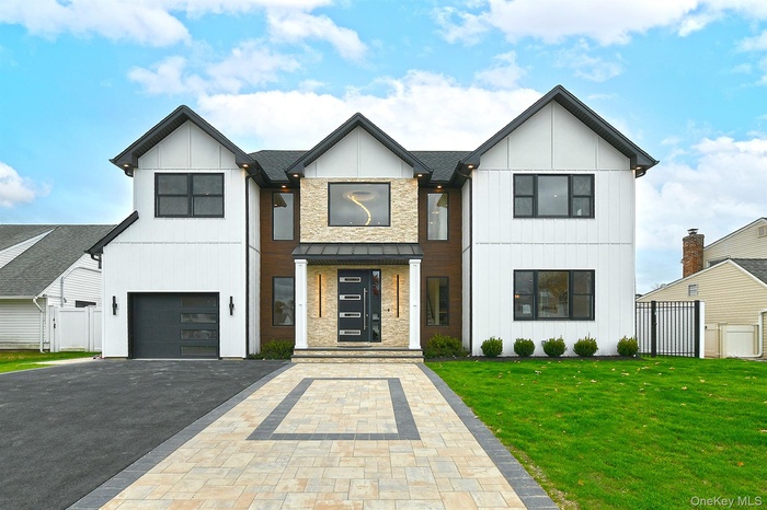 Modern farmhouse with driveway, board and batten siding, a garage, and a standing seam roof