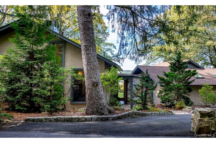 View of front of house featuring stucco siding, roof with shingles, and stone siding