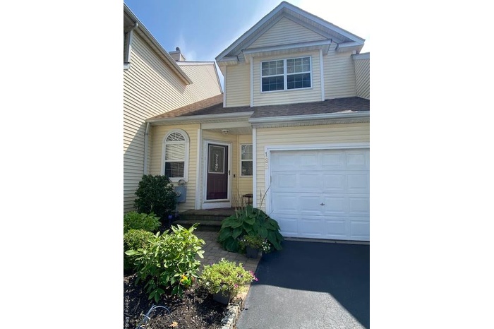 View of front of house featuring driveway and a shingled roof