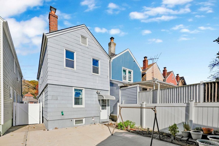 Rear view of property featuring a fenced backyard, a chimney, and a gate