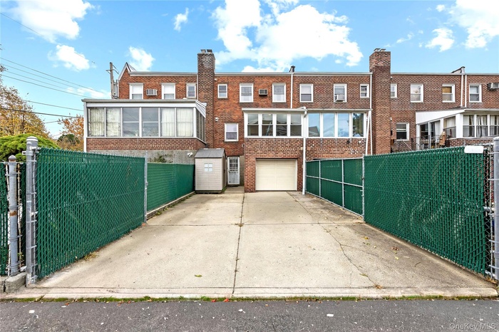 Back of property with brick siding, driveway, a chimney, and an attached garage