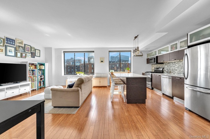 Kitchen with stainless steel appliances, pendant lighting, light wood finished floors, open floor plan, and decorative backsplash