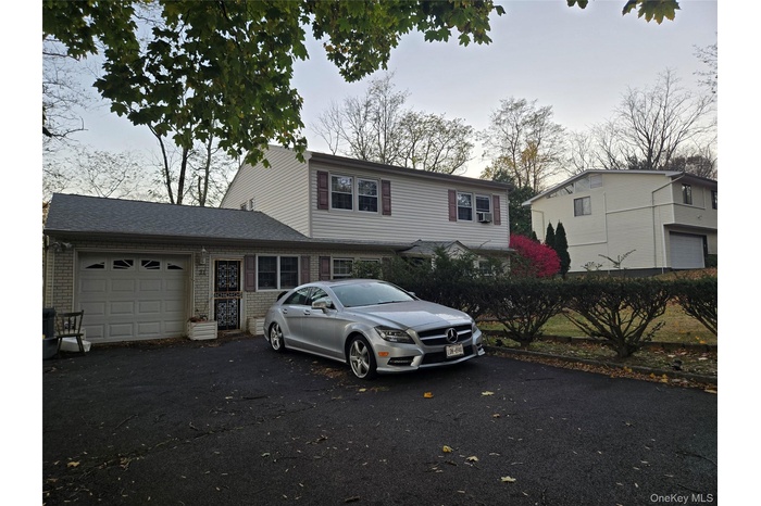 View of front of house featuring driveway, a garage, and brick siding